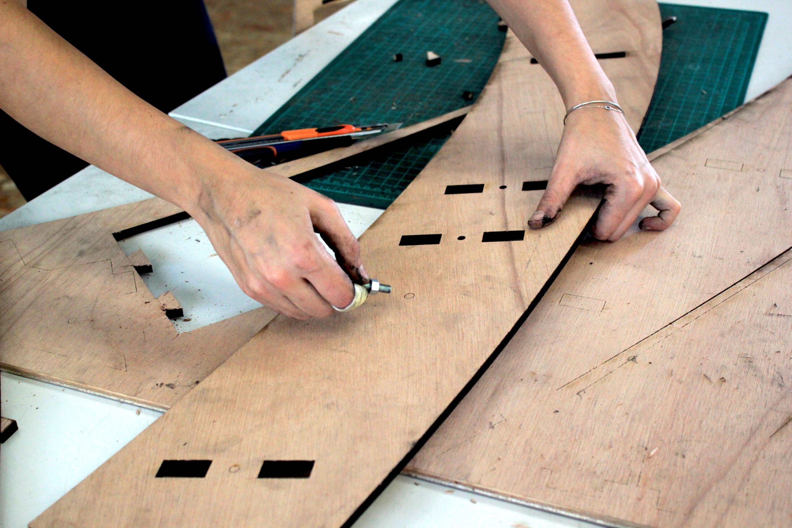 détail de mains bricolant des planches de bois dans un atleier
